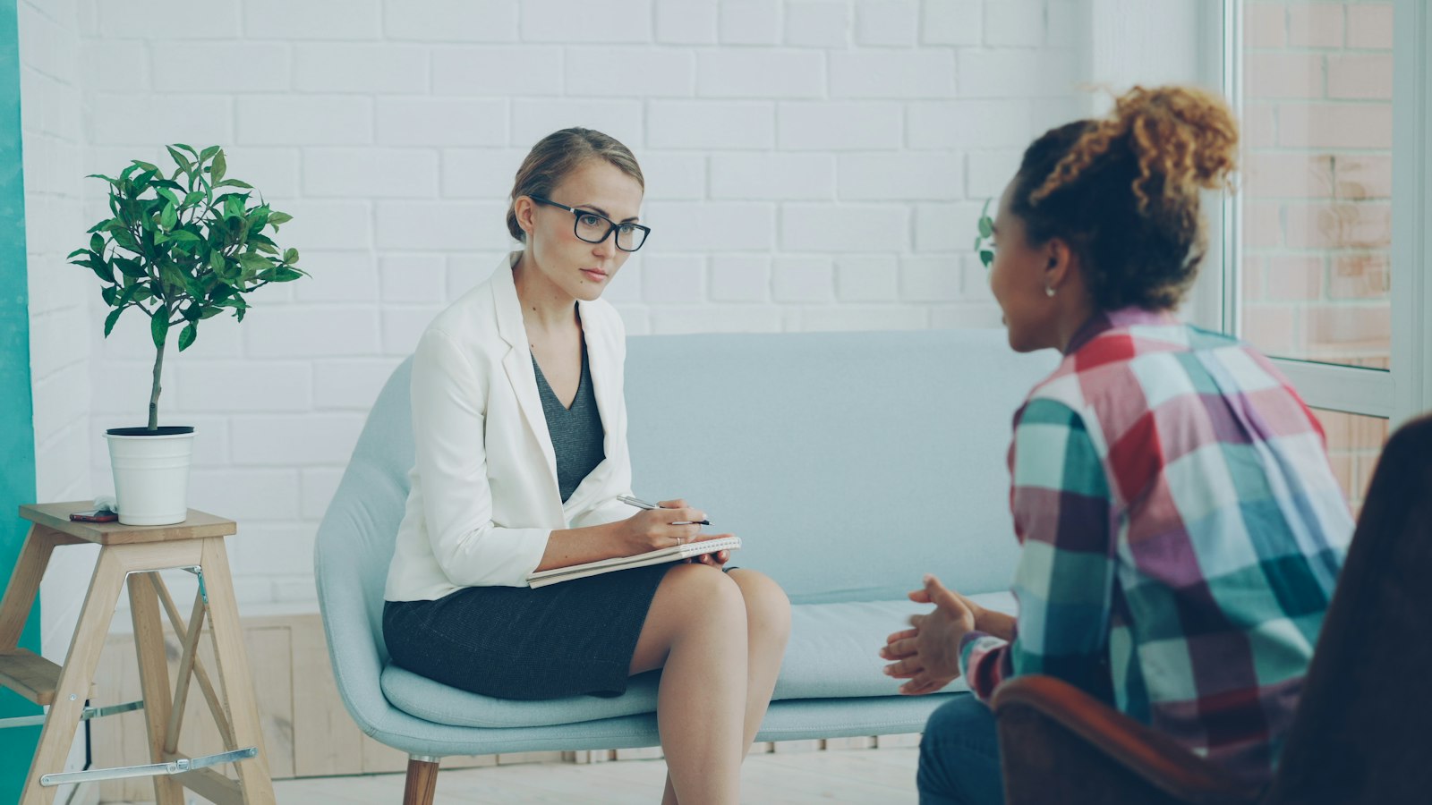 A doctor and a young woman talking in a bright consulting room