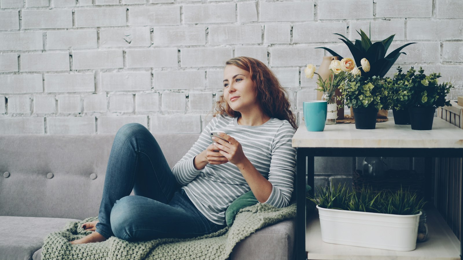 A woman on a sofa at home with her phone in her hands